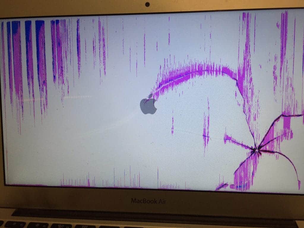 MacBook Air has cracked screen with pink lines.