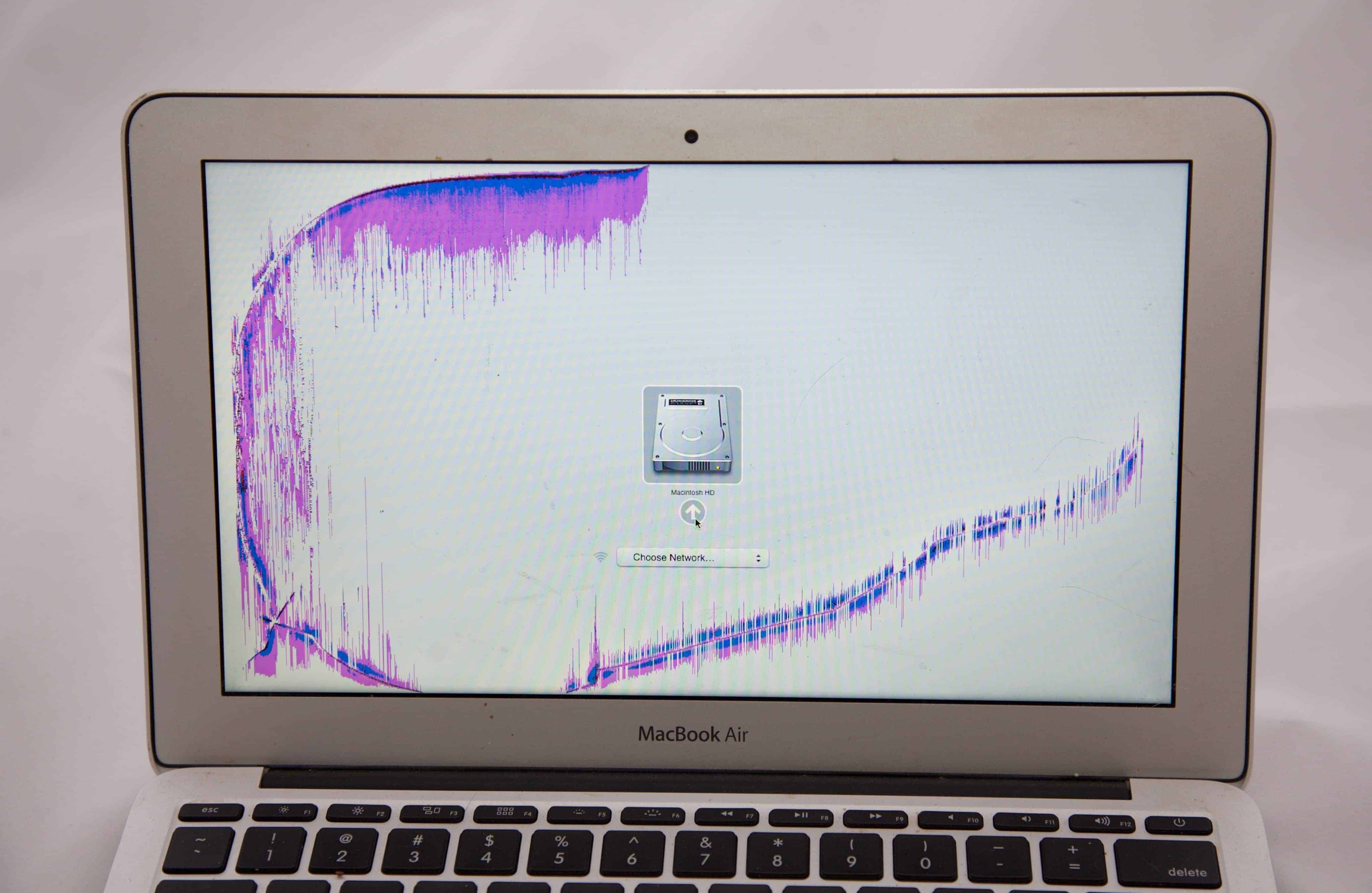 MacBook Air 11" with pink and blue discoloration around crack.