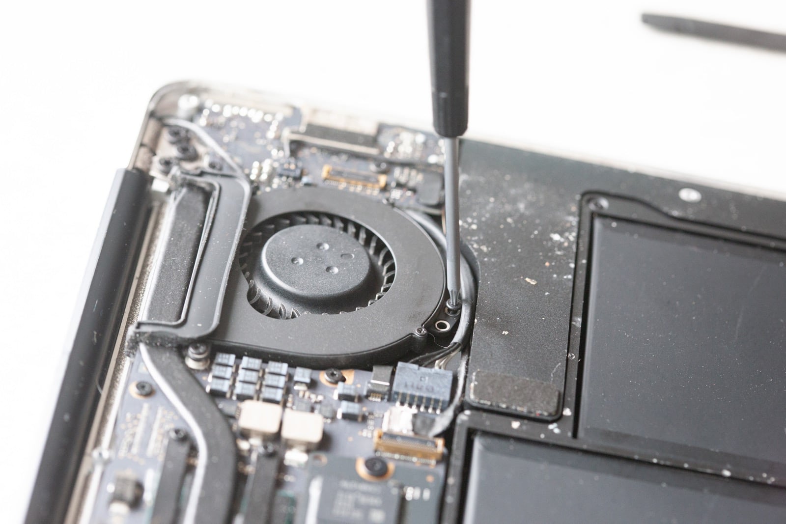 Removing bottom screw on MacBook Air fan assembly.